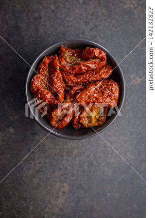 Sun-Dried Tomatoes in Olive Oil in a Bowl Over Dark Textured Surface, Mediterranean Ingredient Sun-Dried Tomatoes in Olive Oil in a Bowl Over Dark Textured Surface, Mediterranean Ingredient 142132827