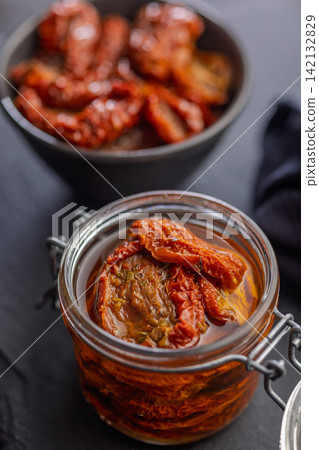 Sun-Dried Tomatoes in Jar with Olive Oil on Slate Board, Rustic Preserved Tomato Close-Up Sun-Dried Tomatoes in Jar with Olive Oil on Slate Board, Rustic Preserved Tomato Close-Up 142132829