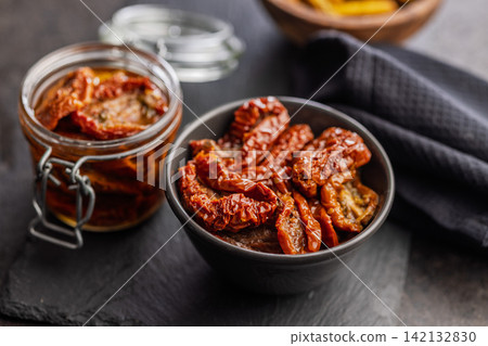 Sun-Dried Tomatoes in Olive Oil Jar and Bowl on Dark Slate for Gourmet Mediterranean Cooking Sun-Dried Tomatoes in Olive Oil Jar and Bowl on Dark Slate for Gourmet Mediterranean Cooking 142132830