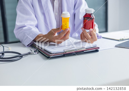Doctor or pharmacist holding medication bottles while writing prescription order in clinic. Doctor or pharmacist holding medication bottles while writing prescription order in clinic. 142132858