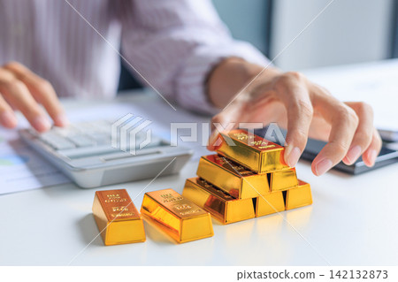 Investor Hands Stacking Counting Gold Bullion Bars on Desk while Calculating Profit. Secure Financial Investment and Wealth Preservation Concept. Investor Hands Stacking Counting Gold Bullion Bars on Desk while Calculating Profit. Secure Financial Investment and Wealth Preservation Concept. 142132873
