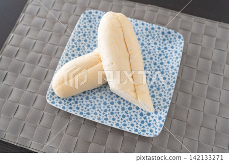 A set of white bread rolls placed on a plate. 142133271