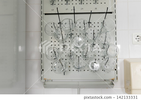 numbered pegboard rack with glass flasks in laboratory numbered pegboard rack with glass flasks in laboratory 142133331