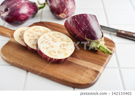 Three fresh purple eggplants on wooden cutting board Three fresh purple eggplants on wooden cutting board 142133401