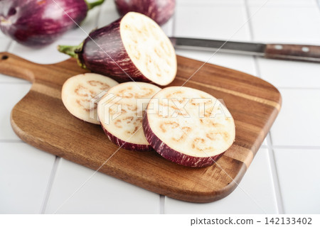 Three fresh purple eggplants on wooden cutting board Three fresh purple eggplants on wooden cutting board 142133402
