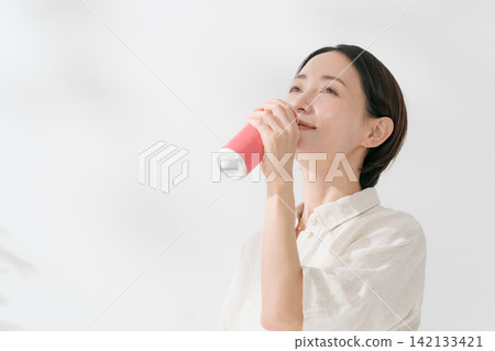 一名女子正在喝罐裝飲料 一名女子正在喝罐裝飲料 142133421