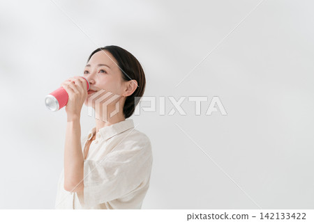一名女子正在喝罐裝飲料 一名女子正在喝罐裝飲料 142133422