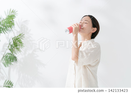 一名女子正在喝罐裝飲料 一名女子正在喝罐裝飲料 142133423
