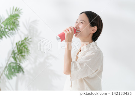 一名女子正在喝罐裝飲料 142133425