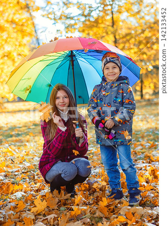 Mother and son enjoy time together under a colorful umbrella on an autumn day in a park Mother and son enjoy time together under a colorful umbrella on an autumn day in a park 142133452
