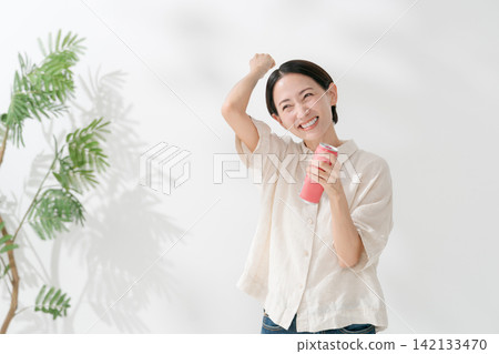 一名女子擺出勝利姿勢，喝起了飲料。 142133470