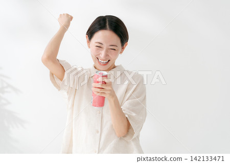 一名女子擺出勝利姿勢,喝起了飲料。 一名女子擺出勝利姿勢,喝起了飲料。 142133471