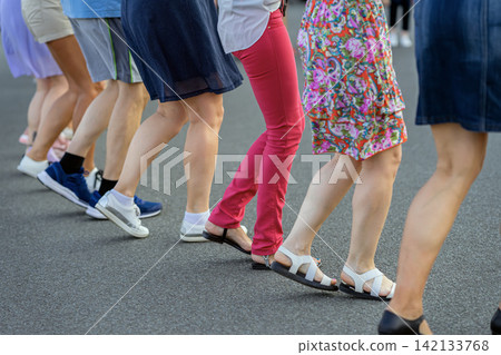 Women Dancing Horo in Row on Street. Dancing in row, traditional horo dance outdoors in Bulgaria. Cultural group movement scene focused on legs, rhythm, community, folk dance tradition Women Dancing Horo in Row on Street. Dancing in row, traditional horo dance outdoors in Bulgaria. Cultural group movement scene focused on legs, rhythm, community, folk dance tradition 142133768