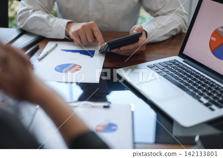 Business professionals reviewing financial documents contain data of pie charts and graphs. Business professionals reviewing financial documents contain data of pie charts and graphs. 142133801