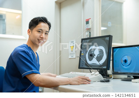 一名放射科醫生正在進行 CT 掃描,直視鏡頭(肖像)。 一名放射科醫生正在進行 CT 掃描,直視鏡頭(肖像)。 142134651