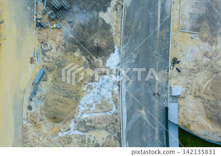 Workers are preparing road at construction site with piles of dirt building materials scattered around. Workers are preparing road at construction site with piles of dirt building materials scattered around. 142135831