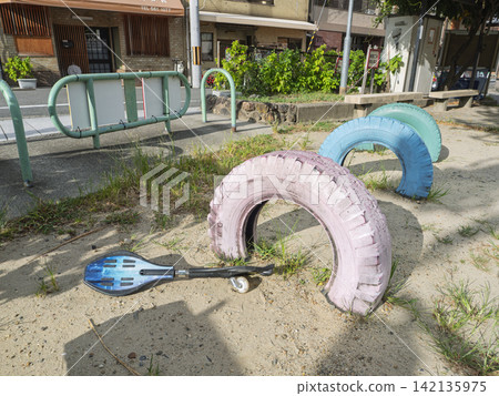 公園的沙地上擺放著色彩鮮豔的彩繪輪胎遊樂設施和滑板。 公園的沙地上擺放著色彩鮮豔的彩繪輪胎遊樂設施和滑板。 142135975