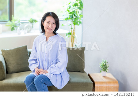 Portrait of a middle-aged woman sitting on a sofa Portrait of a middle-aged woman sitting on a sofa 142136215