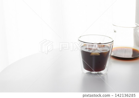 Image of a home cafe | Iced coffee and a double-walled glass placed in a room with a white base. Image of a home cafe | Iced coffee and a double-walled glass placed in a room with a white base. 142136285