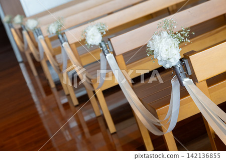 A wedding ceremony with a chapel aisle decorated with fresh flowers. A wedding ceremony with a chapel aisle decorated with fresh flowers. 142136855