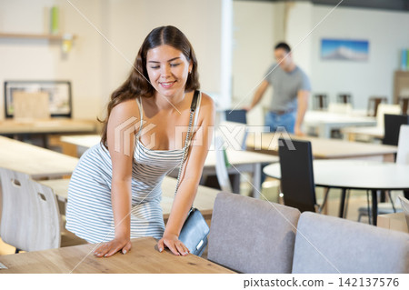 In furniture showroom,woman inspects sliding kitchen table In furniture showroom,woman inspects sliding kitchen table 142137576
