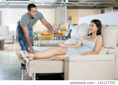 Happy young couple choosing a soft new sofa in furniture store 142137705