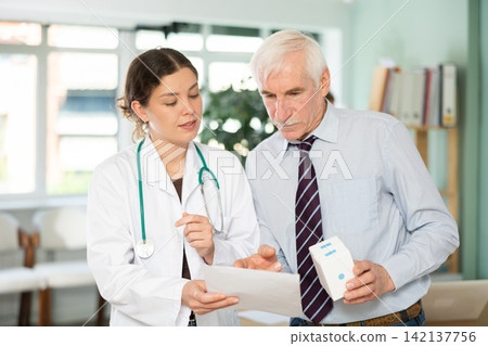Female doctor discusses medical tests with elderly man in clinic Female doctor discusses medical tests with elderly man in clinic 142137756