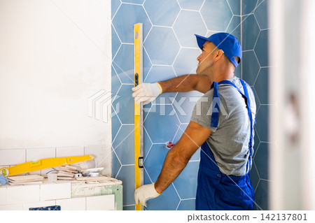 Repairer using spirit level on wall, working on home improvement Repairer using spirit level on wall, working on home improvement 142137801