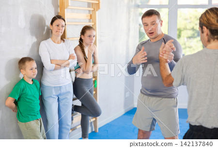 Man coach shows family students technique of performing painful modus with help of wringing hand Man coach shows family students technique of performing painful modus with help of wringing hand 142137840