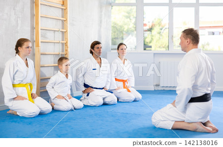 Family in gym at group karate training with trainer are in sitting position 142138016
