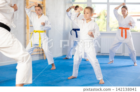 Kid boy and his family repeat movements and learn fighting techniques during martial arts lesson Kid boy and his family repeat movements and learn fighting techniques during martial arts lesson 142138041
