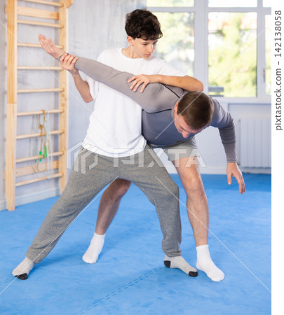 Teenage boy and middle-aged man training arm twist technique during self-defense courses Teenage boy and middle-aged man training arm twist technique during self-defense courses 142138058