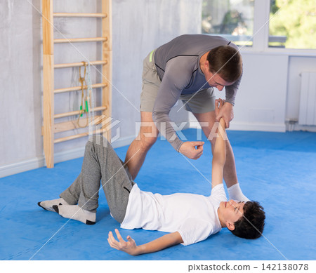 Teenage boy and middle-aged man training throwing method during self-defense courses Teenage boy and middle-aged man training throwing method during self-defense courses 142138078