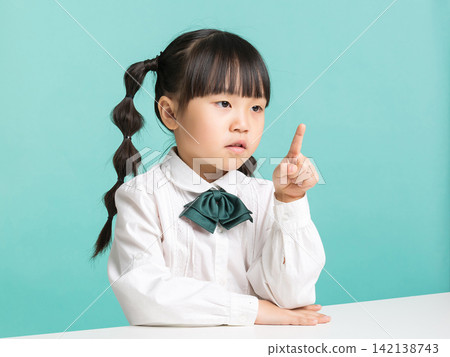 Thoughtful Asian schoolgirl pointing finger thinking isolated on blue background, education idea concept Thoughtful Asian schoolgirl pointing finger thinking isolated on blue background, education idea concept 142138743