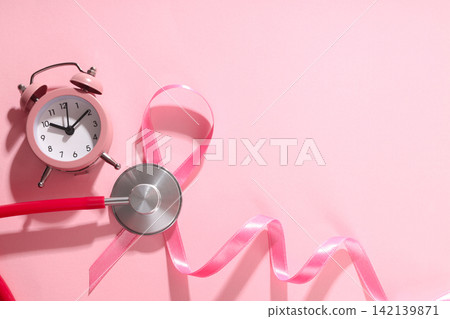 Pink ribbon, alarm clock, and stethoscope on light background Pink ribbon, alarm clock, and stethoscope on light background 142139871