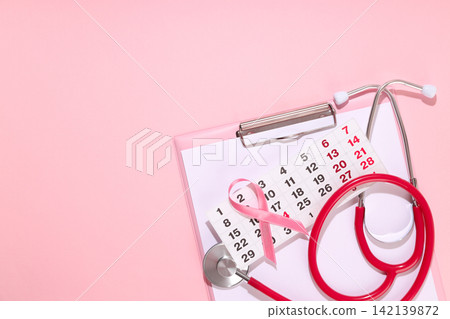Calendar with pink ribbon and stethoscope on pink background Calendar with pink ribbon and stethoscope on pink background 142139872
