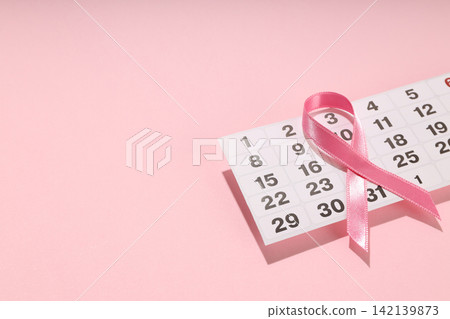 Calendar page with pink ribbon on soft pink surface Calendar page with pink ribbon on soft pink surface 142139873