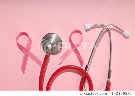 Red-tubed stethoscope next to pink ribbons on pink 142139875