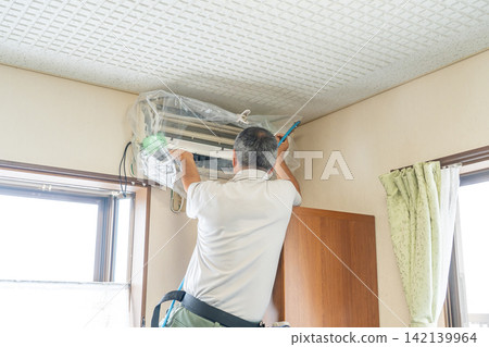 Air conditioner cleaning; a man from the air conditioner maintenance company. Air conditioner cleaning; a man from the air conditioner maintenance company. 142139964