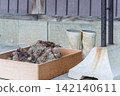 Taro roots with soil still attached, in a wooden box, and work boots. 142140611
