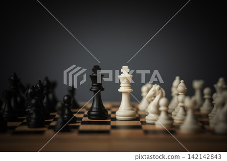 white and black kings facing off on chess board 142142843