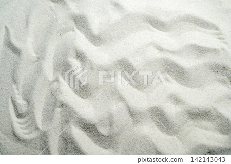 An overhead view of fine white sand showing natural wavy ripple patterns, creating a clean, minimalist texture. Summer, natural or texture background 142143043