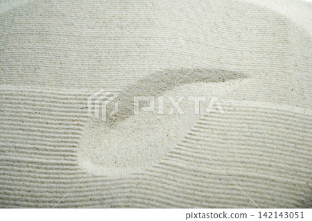 Close-up of raked white sand with a smooth curved stroke, representing mindfulness, Zen philosophy, and peaceful meditation. Summer, natural or texture background Close-up of raked white sand with a smooth curved stroke, representing mindfulness, Zen philosophy, and peaceful meditation. Summer, natural or texture background 142143051