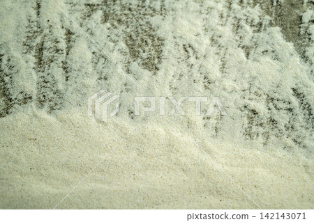 Close-up texture of fine white sand scattered over a rough, dark stone surface. Summer, natural or texture background Close-up texture of fine white sand scattered over a rough, dark stone surface. Summer, natural or texture background 142143071