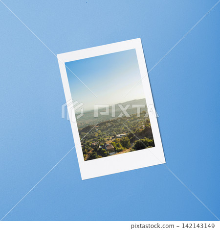 An instant photo of a scenic mountain landscape placed on a blue textured background. Tourism Day Concept An instant photo of a scenic mountain landscape placed on a blue textured background. Tourism Day Concept 142143149