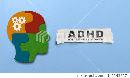 ADHD Awareness Month concept featuring a puzzle-shaped head profile with gears next to a torn paper sign on a blue background. Concept of ADHD Awareness Month ADHD Awareness Month concept featuring a puzzle-shaped head profile with gears next to a torn paper sign on a blue background. Concept of ADHD Awareness Month 142143327