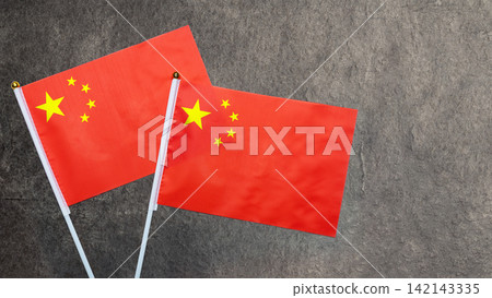 Two small flags of the People's Republic of China on a dark gray textured stone background with copy space. China National Day celebration Two small flags of the People's Republic of China on a dark gray textured stone background with copy space. China National Day celebration 142143335