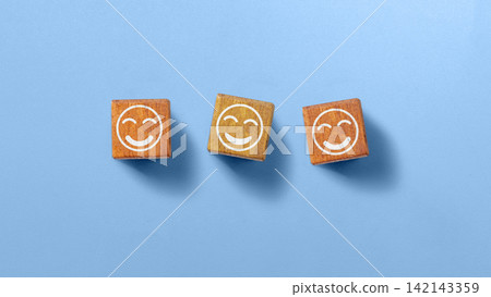 Wooden cubes with happy smileys on a blue background, symbolizing positive rating, customer satisfaction, and feedback. Concept of World Smile Day Wooden cubes with happy smileys on a blue background, symbolizing positive rating, customer satisfaction, and feedback. Concept of World Smile Day 142143359