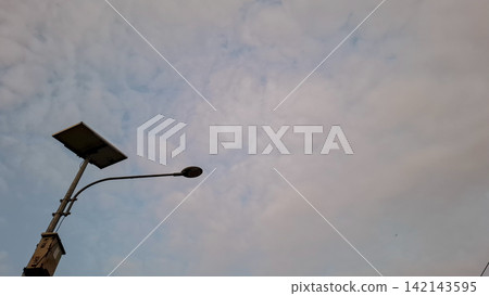 Solar Street Light and Panel Against Overcast Sky Solar Street Light and Panel Against Overcast Sky 142143595