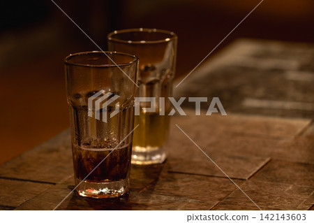 暖色木桌上的兩只玻璃飲料杯 暖色木桌上的兩只玻璃飲料杯 142143603
